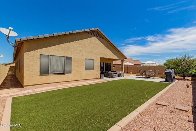 back of house featuring outdoor lounge area, a lawn, and a patio