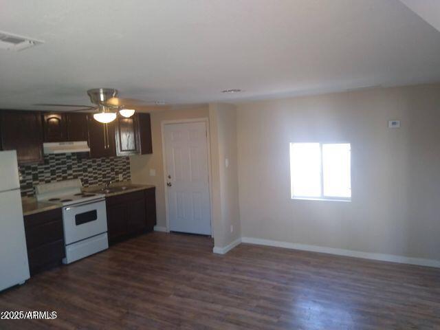 kitchen with white appliances, dark brown cabinetry, dark hardwood / wood-style floors, and decorative backsplash