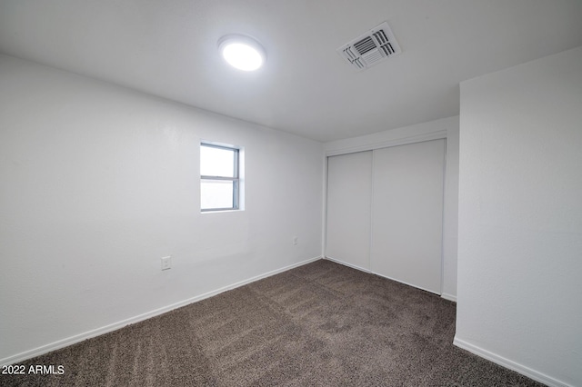 unfurnished bedroom featuring a closet and dark colored carpet