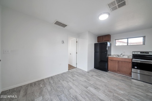 kitchen featuring light hardwood / wood-style flooring, sink, stainless steel range with electric cooktop, and black fridge