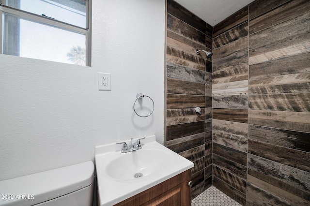 bathroom featuring toilet, vanity, and a tile shower