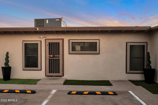 exterior entry at dusk with central air condition unit and a patio area