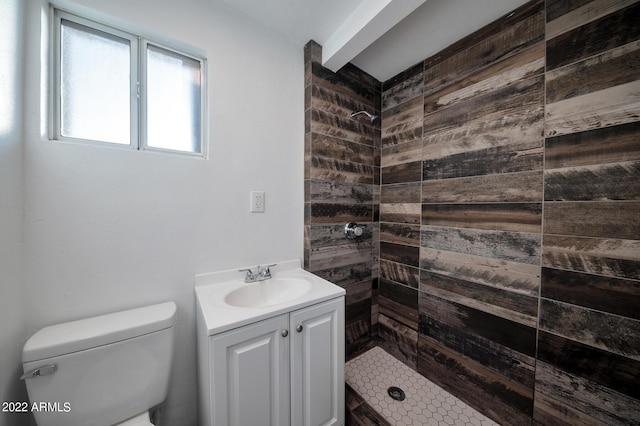 bathroom with tiled shower, vanity, and toilet