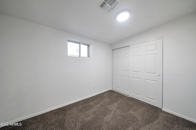 unfurnished bedroom featuring a closet and dark carpet