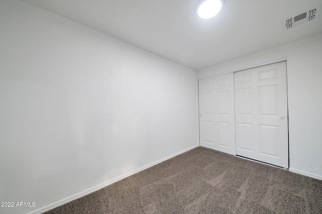 unfurnished bedroom with a closet and dark colored carpet