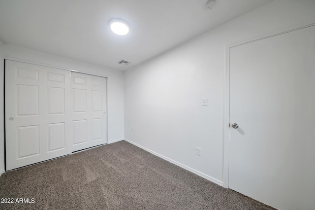 unfurnished bedroom with a closet and dark colored carpet