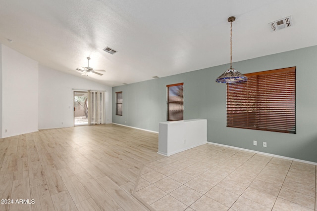 spare room featuring a textured ceiling, vaulted ceiling, ceiling fan, and light hardwood / wood-style flooring