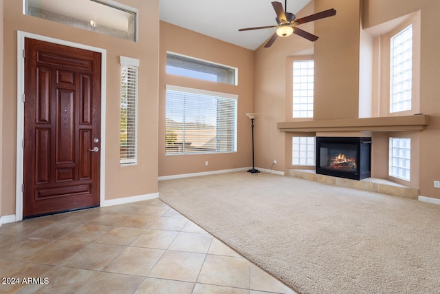 carpeted foyer entrance featuring ceiling fan and a towering ceiling