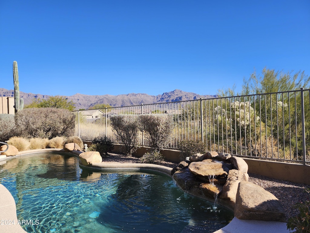 view of swimming pool featuring fence and a mountain view