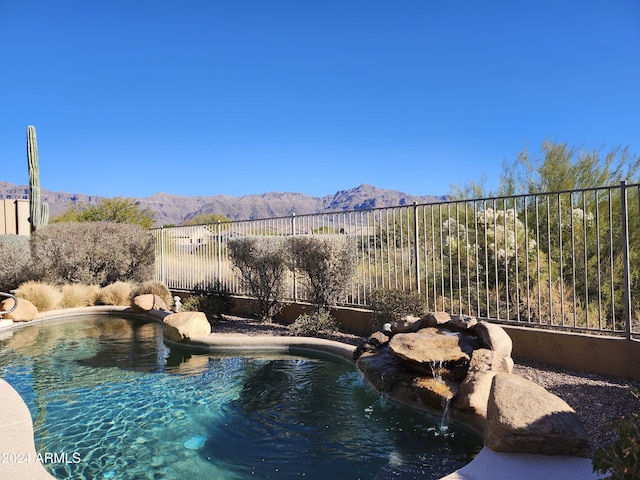 view of swimming pool featuring fence and a mountain view