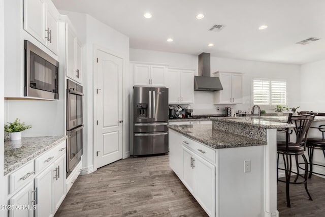 2052 E Scorpio Pl, Chandler, AZ 85249 - kitchen with stainless steel appliances, wall chimney range hood, a kitchen breakfast bar, an island with sink, and white cabinetry
