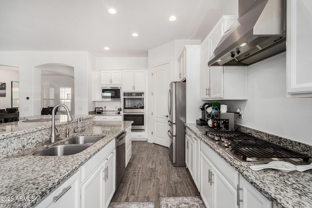 2052 E Scorpio Pl, Chandler, AZ 85249 - kitchen featuring wall chimney exhaust hood, stainless steel appliances, a sink, arched walkways, and white cabinetry