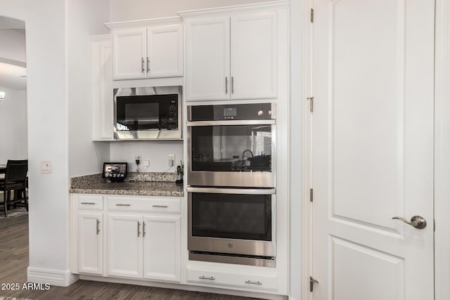 2052 E Scorpio Pl, Chandler, AZ 85249 - kitchen with double oven, built in microwave, dark wood-style floors, white cabinetry, and dark stone countertops