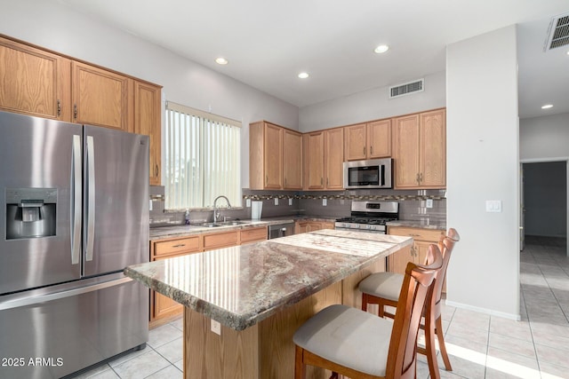 kitchen featuring light tile patterned flooring, sink, a kitchen island, stainless steel appliances, and backsplash