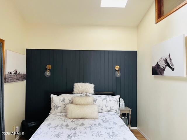 bedroom with a skylight and wood finished floors