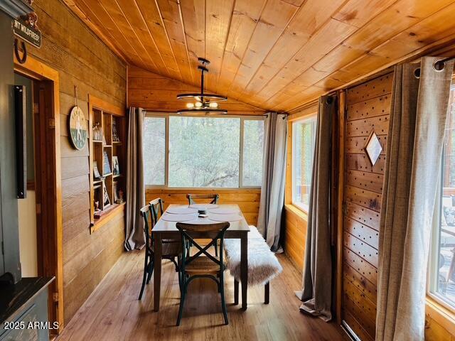 dining room featuring wooden ceiling, wood finished floors, wood walls, and lofted ceiling