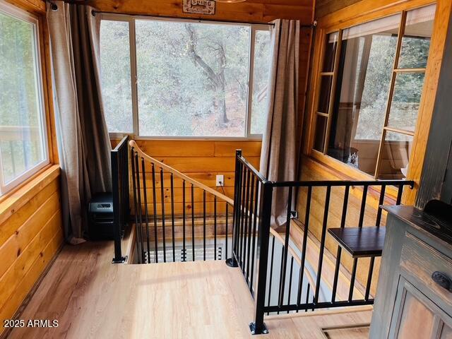 stairs with wooden walls and wood finished floors