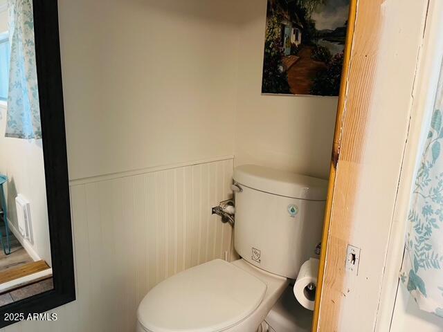 bathroom featuring wainscoting and toilet