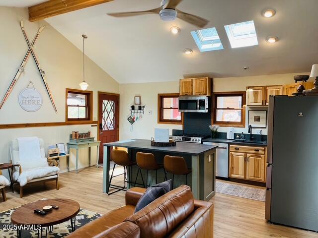 kitchen with dark countertops, a center island, a breakfast bar, stainless steel appliances, and a sink