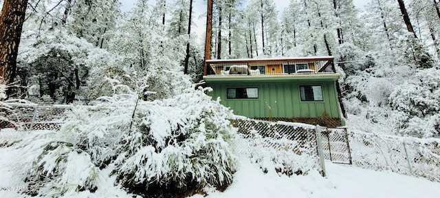 snow covered structure with fence and a wooded view