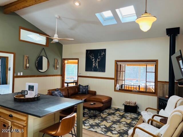 interior space with wood finished floors, vaulted ceiling with beams, ceiling fan, and wainscoting