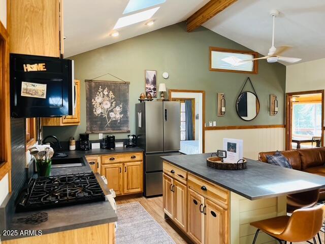 kitchen with a sink, stovetop, dark countertops, and freestanding refrigerator