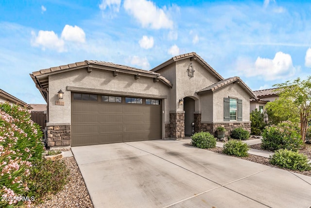 mediterranean / spanish-style house with a tile roof, stucco siding, driveway, stone siding, and an attached garage