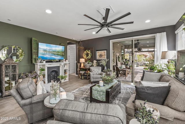 living room featuring visible vents, ceiling fan, recessed lighting, a fireplace, and wood finished floors