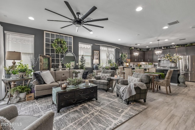 living area featuring light wood-type flooring, visible vents, a ceiling fan, and recessed lighting