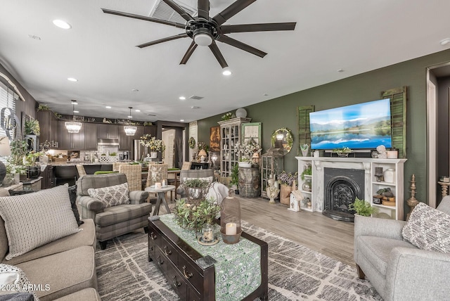 living area with wood finished floors, visible vents, a fireplace, recessed lighting, and ceiling fan