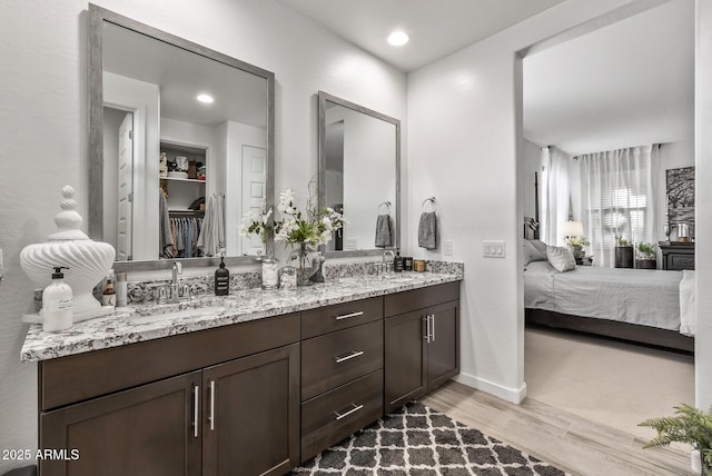 bathroom featuring double vanity, recessed lighting, ensuite bathroom, wood finished floors, and a sink