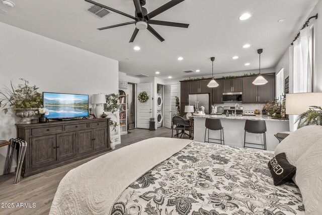 bedroom with visible vents, light wood-style flooring, a sink, freestanding refrigerator, and recessed lighting