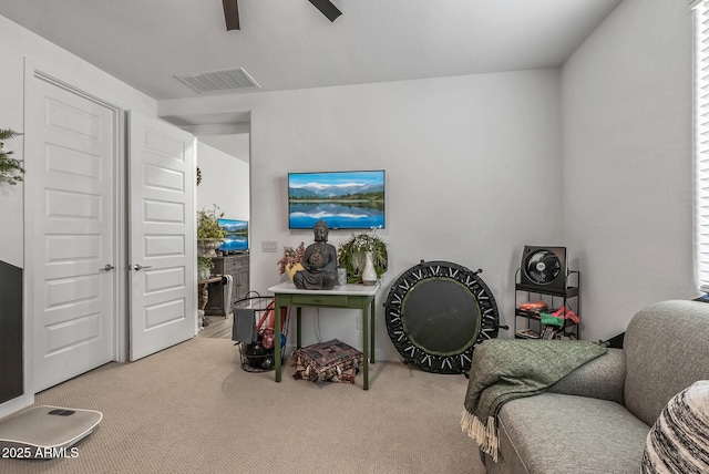 living area featuring visible vents, ceiling fan, and carpet