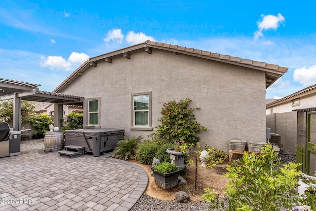 back of house featuring a patio area, a hot tub, and stucco siding