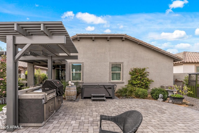 view of patio / terrace featuring area for grilling, an outdoor kitchen, a hot tub, and a pergola