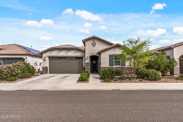 mediterranean / spanish-style home featuring a tile roof, stucco siding, driveway, stone siding, and an attached garage