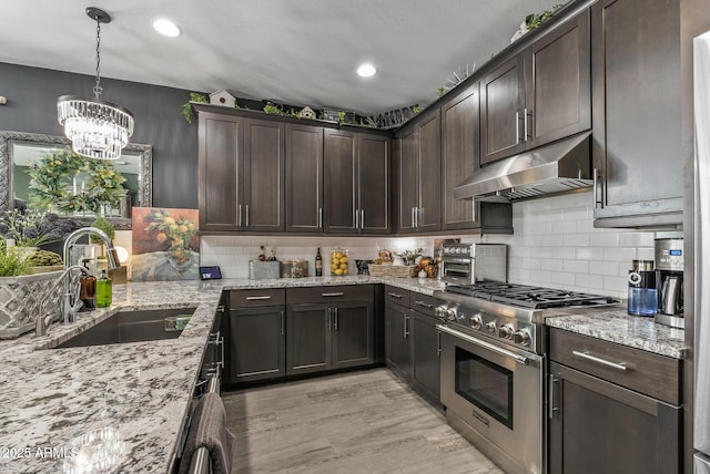 kitchen with under cabinet range hood, high end stove, dark brown cabinetry, and a sink