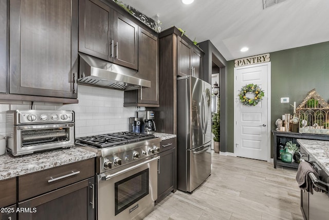 kitchen with under cabinet range hood, appliances with stainless steel finishes, and dark brown cabinets