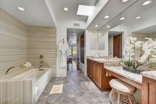 bathroom with vanity, a tub to relax in, and a skylight