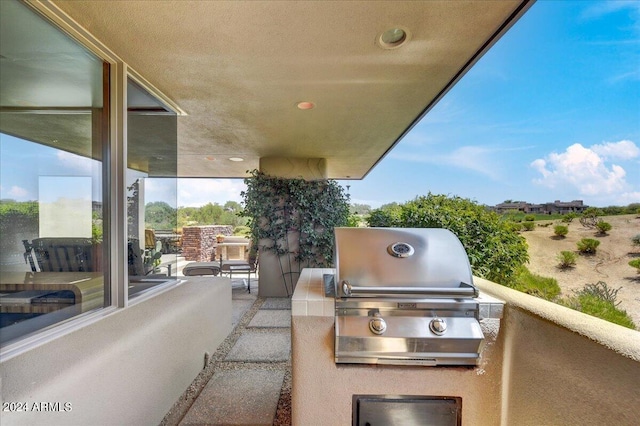 view of patio featuring a grill, a balcony, and an outdoor kitchen