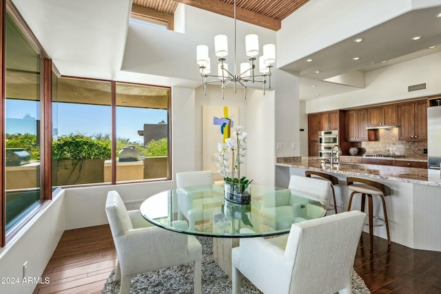 dining room with a towering ceiling, dark hardwood / wood-style flooring, and a chandelier