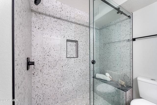 bathroom featuring a textured ceiling, toilet, and an enclosed shower