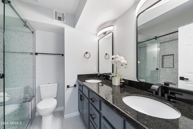 bathroom featuring a shower with door, vanity, and toilet