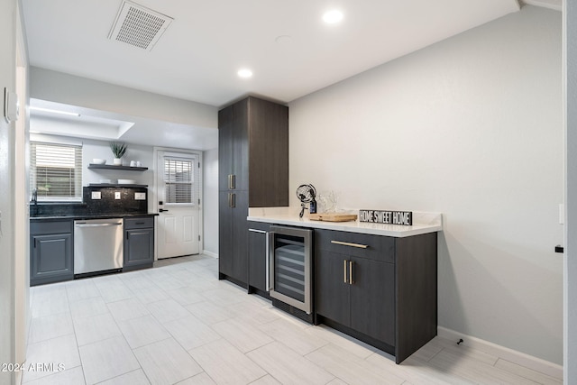 kitchen with stainless steel dishwasher, dark brown cabinets, beverage cooler, and tasteful backsplash