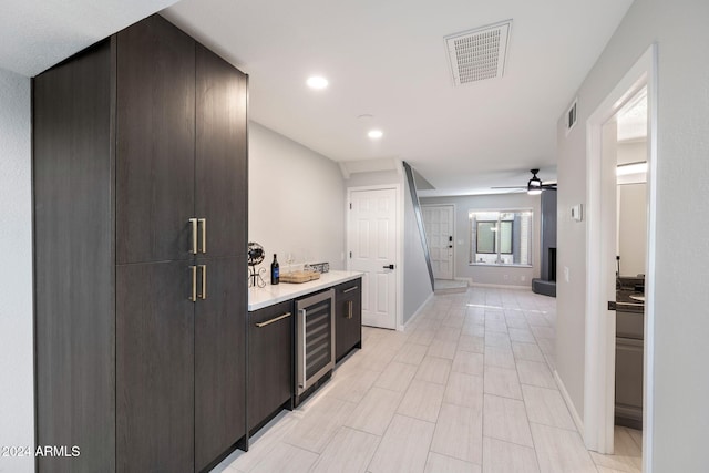 bar with wine cooler, ceiling fan, and dark brown cabinets