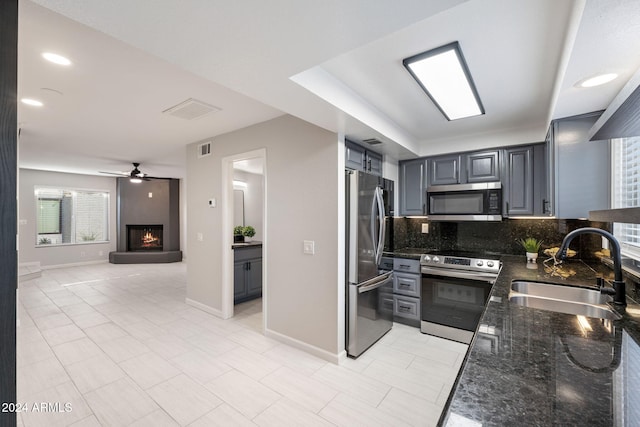 kitchen with decorative backsplash, dark stone counters, stainless steel appliances, sink, and gray cabinets