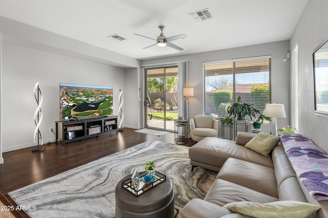 living room featuring ceiling fan, visible vents, baseboards, and wood finished floors