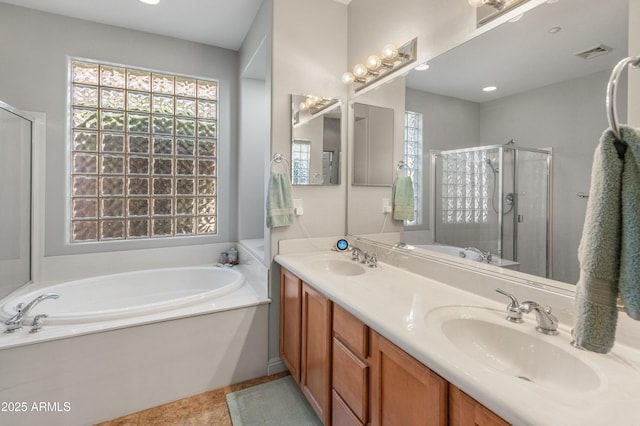 bathroom featuring a shower stall, a garden tub, visible vents, and a sink