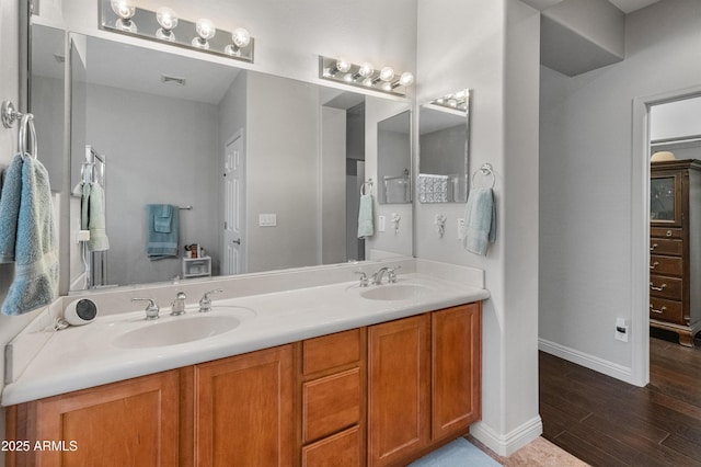 bathroom with double vanity, wood finished floors, visible vents, and a sink