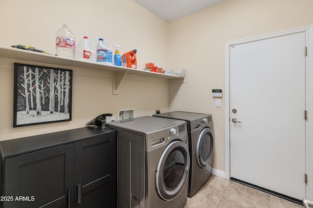 laundry room featuring light tile patterned flooring, cabinet space, baseboards, and washer and clothes dryer